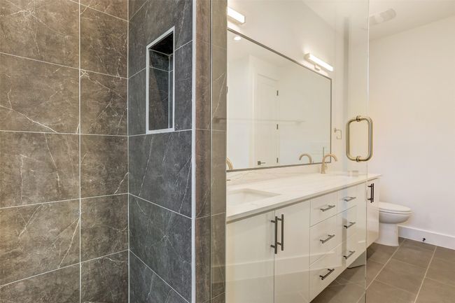 Full bathroom with toilet, double vanity, a tile shower, and tile patterned flooring | Image 15