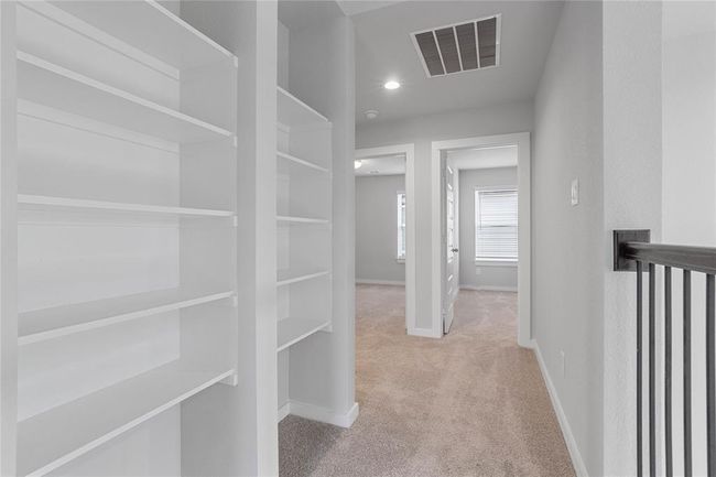 Second floor features built in shelves, plush carpet, high vaulted ceiling, recessed lighting, and neutral paint. | Image 14