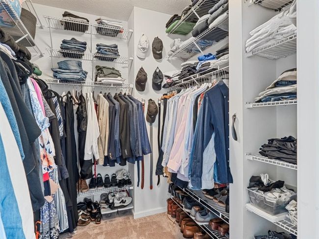 This impressive primary walk-in closet offers exceptional organization and storage space with built-in shelving, hanging racks, and dedicated compartments for shoes and accessories. | Image 19