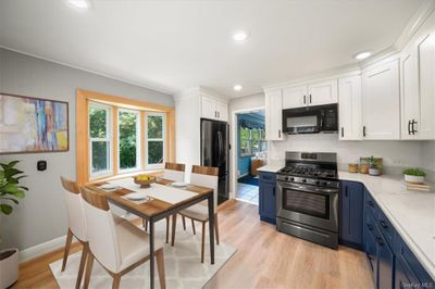 Kitchen featuring a wealth of natural light, black appliances, blue cabinets, and white cabinetry | Image 2