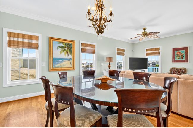 Dining room with ornamental molding, light wood-type flooring, a chandelier, and a ceiling fan | Image 9