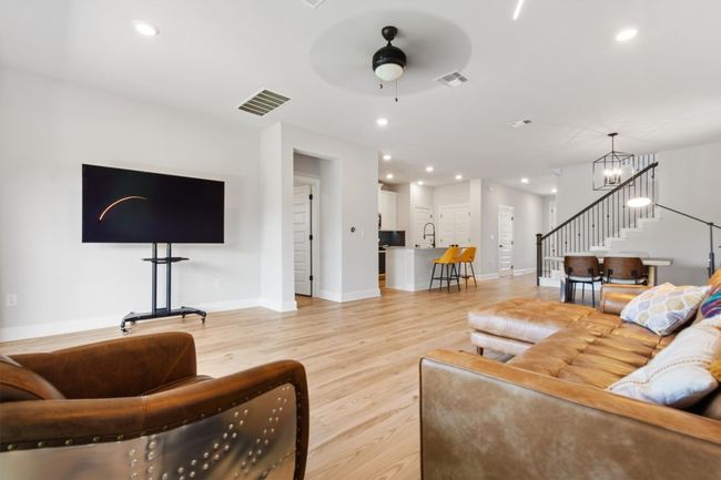 Living area featuring stairs, light wood-style flooring, baseboards, ceiling fan, and a chandelier | Image 7