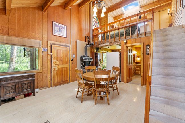 Dining room featuring wood walls, stairs, healthy amount of natural light, high vaulted ceiling, and wood ceiling with exposed beams | Image 7