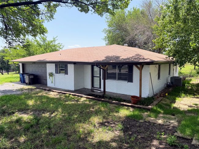 Ranch-style home featuring brick siding, an attached garage, roof with shingles, and gravel driveway | Image 23