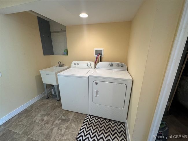 Laundry area featuring washing machine and clothes dryer, laundry sink | Image 11