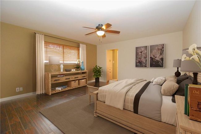 Virtually staged primary bedroom with wood-like tile floors and ceiling fan | Image 11