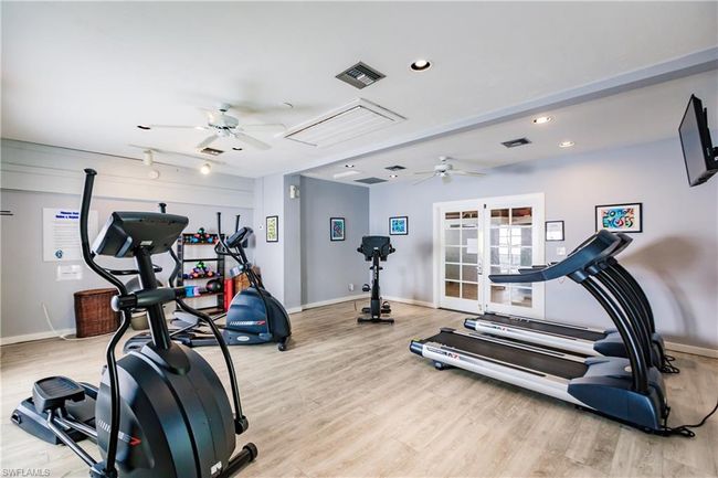 Exercise room featuring ceiling fan, visible vents, and light wood-style flooring | Image 32