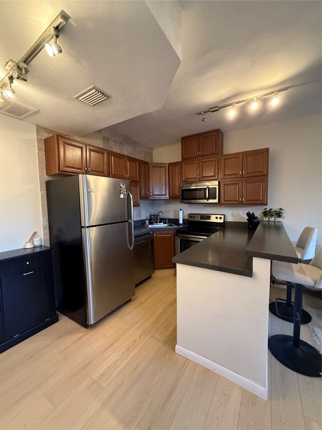 Kitchen featuring refrigerator, dark countertops, visible vents, range, and dishwasher | Image 24