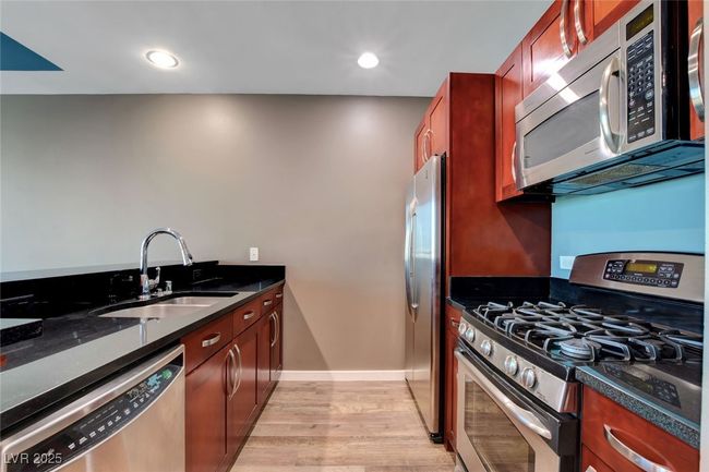 Kitchen featuring light wood finished floors, a sink, baseboards, recessed lighting, and appliances with stainless steel finishes | Image 10