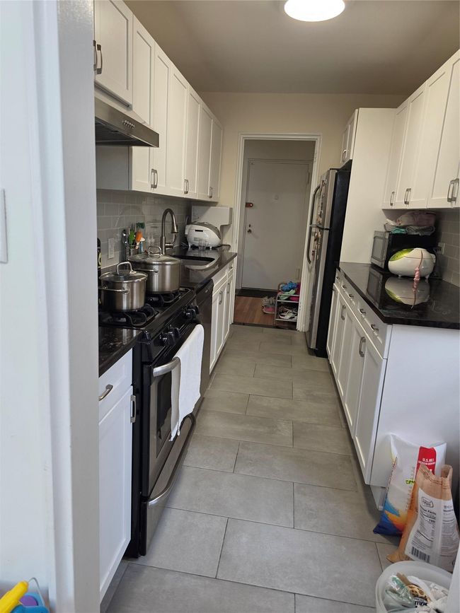 Kitchen with range, range hood, a sink, and dark countertops | Image 8