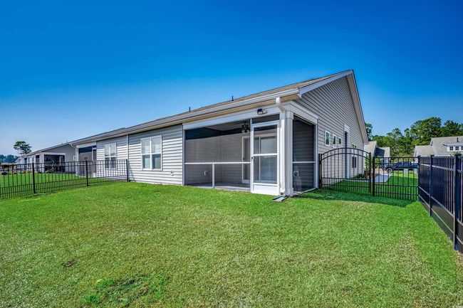 Rear view of house featuring a sunroom, fence, and a lawn | Image 7