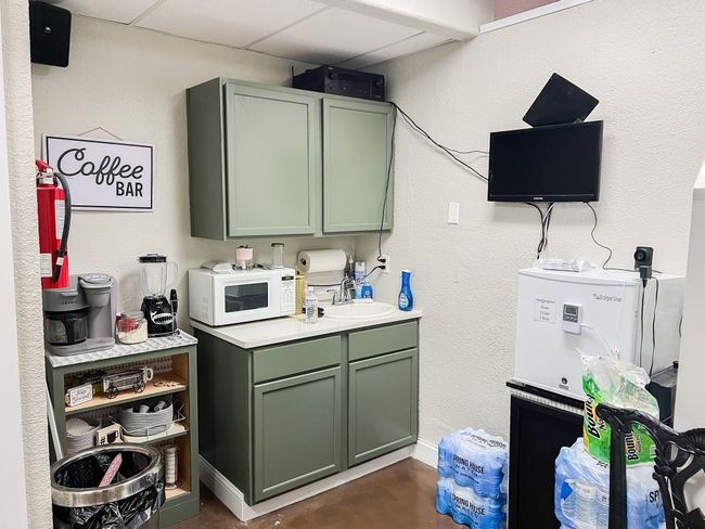 Kitchen featuring white microwave, concrete floors, a sink, green cabinets, and light countertops | Image 15