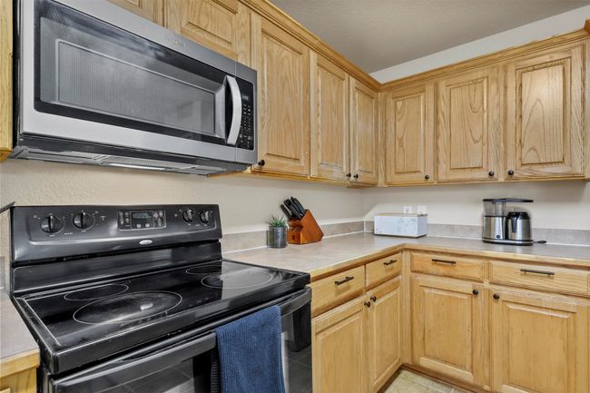 Kitchen featuring light countertops, stainless steel microwave, and black range with electric stovetop | Image 19