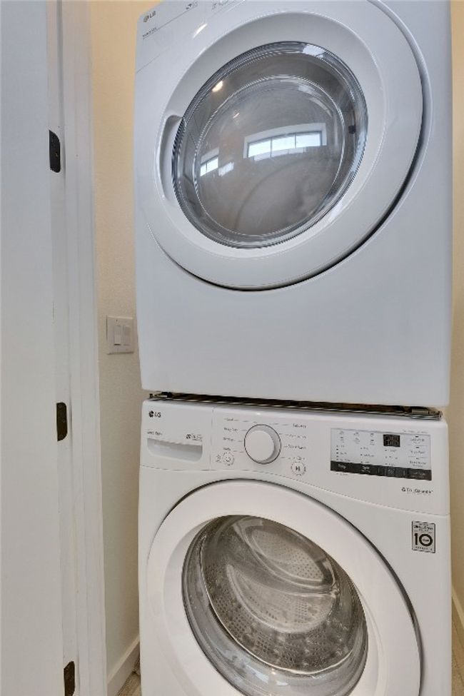 Washroom with stacked washing machine and dryer and baseboards | Image 10