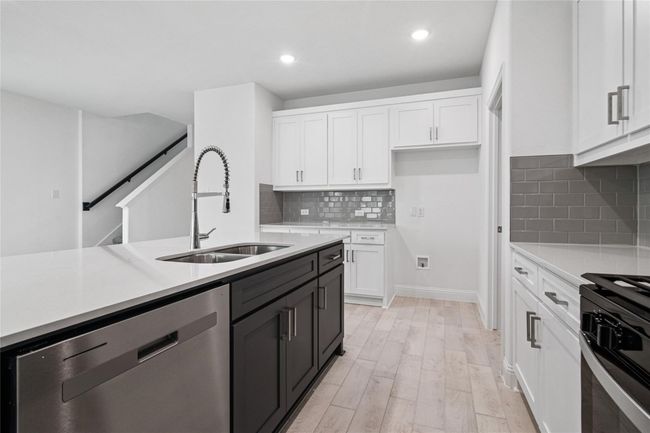 Kitchen featuring white cabinetry, dishwasher, light stone counters, light wood-style floors, and gas stove | Image 23