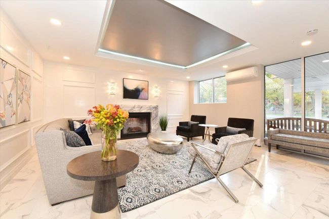 Living area with light marble finish floors, a wall mounted air conditioner, a high end fireplace, recessed lighting, and a tray ceiling | Image 5