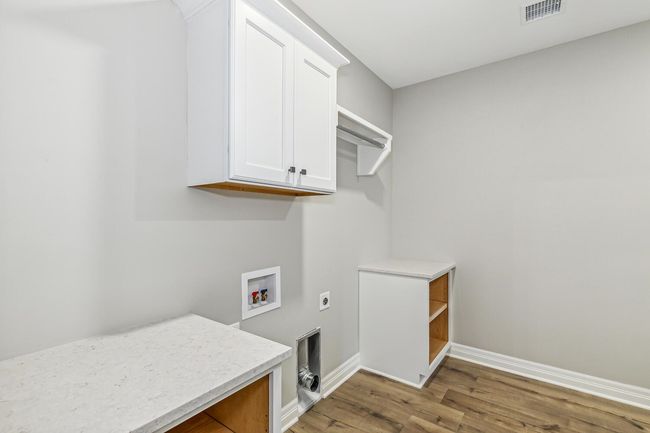 Laundry area featuring electric dryer hookup, hardwood / wood-style floors, cabinets, and hookup for a washing machine | Image 11