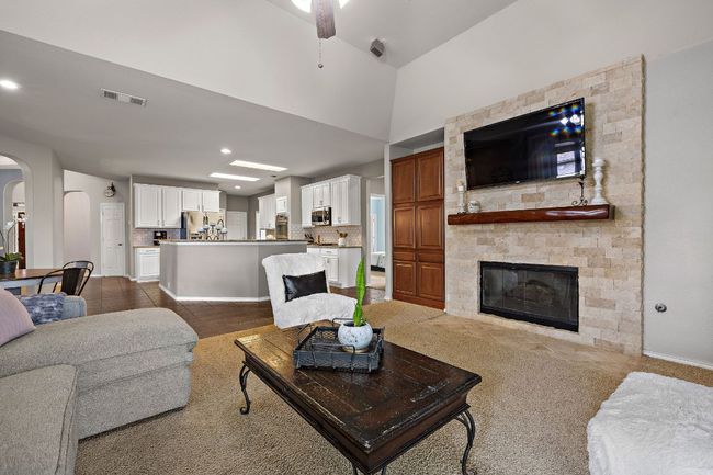 Living room featuring a ceiling fan, arched walkways, a stone fireplace, recessed lighting, and dark colored carpet | Image 10
