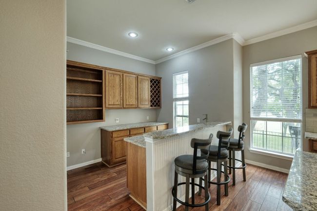 Kitchen with open shelves, brown cabinetry, baseboards, and dark wood-style flooring | Image 15