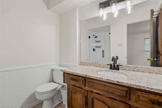 Full bath featuring a stall shower, vanity, toilet, wainscoting, and tile patterned floors | Image 19