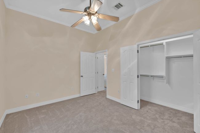 Unfurnished bedroom with crown molding, carpet flooring, a closet, and ceiling fan | Image 24