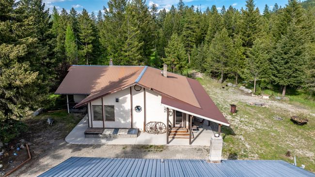 Back of house with metal roof, a view of trees, and a patio area | Image 7