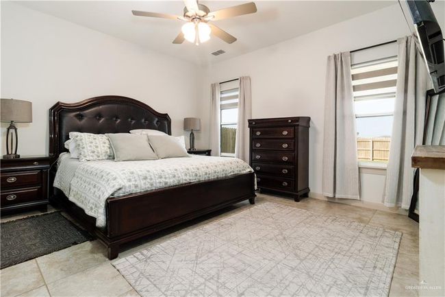 Bedroom with light tile patterned floors, ceiling fan, visible vents, and baseboards | Image 10