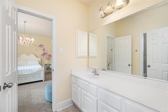 The en-suite bathroom off the secondary bedroom features a spacious layout with ample storage options. The design combines functionality and style, offering everything needed for comfort and convenience. | Image 20