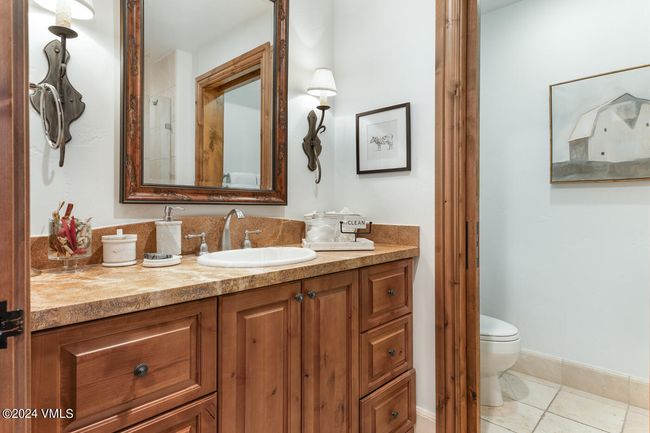 One of several well-appointed bathrooms, this space features rich wood cabinetry, custom lighting, and mountain-inspired design for a warm, welcoming experience. | Image 14