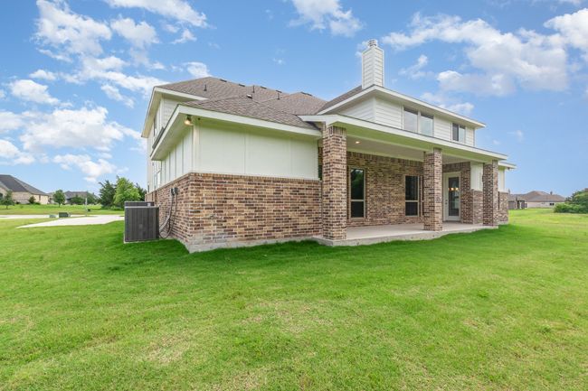 Back of property with brick siding, cooling unit, a patio area, a chimney, and a yard | Image 16