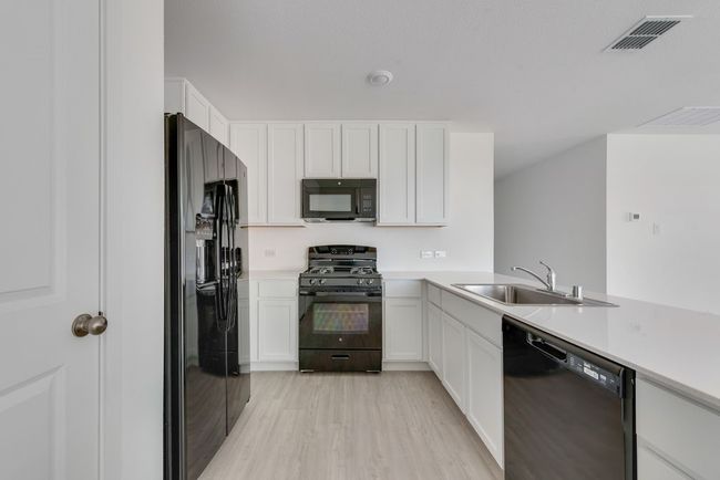 Kitchen featuring black appliances, light countertops, and white cabinets | Image 14