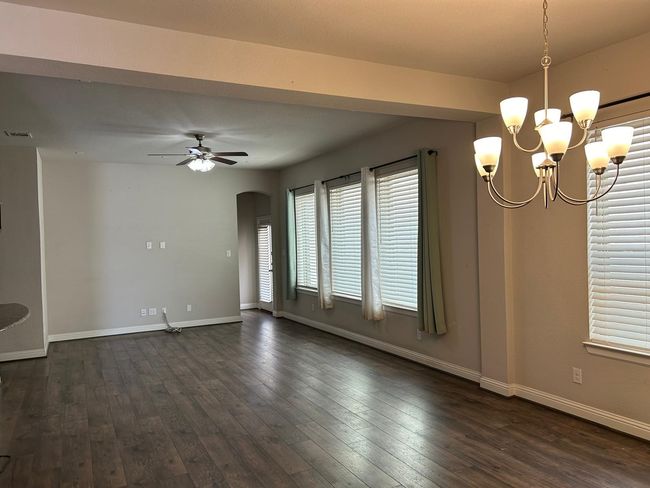 Family room with arched walkways, a chandelier, baseboards, and wood-type flooring | Image 11