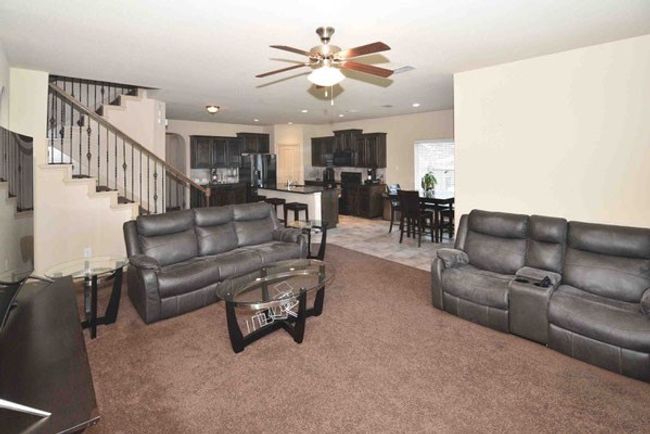 Living room with carpet floors, ceiling fan, and stairs | Image 11