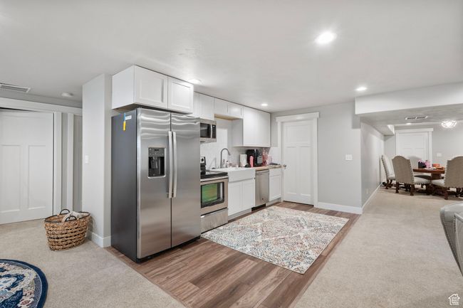 Kitchen featuring appliances with stainless steel finishes, white cabinets, backsplash, recessed lighting, and light wood finished floors | Image 28