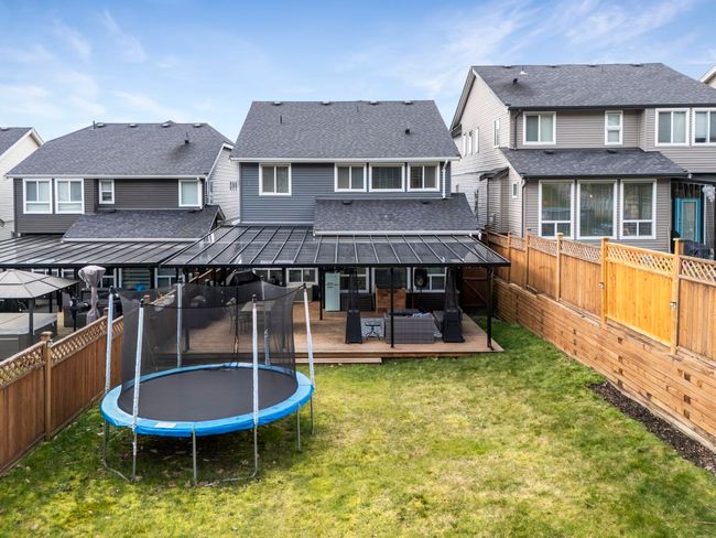 Rear view of property with a wooden deck, a trampoline, a fenced backyard, and a lawn | Image 35