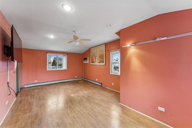 Spare room featuring vaulted ceiling, wood finished floors, a baseboard heating unit, and a ceiling fan | Image 9