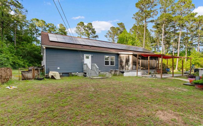 Back of property with a sunroom, roof mounted solar panels, a patio, and roof with shingles | Image 26