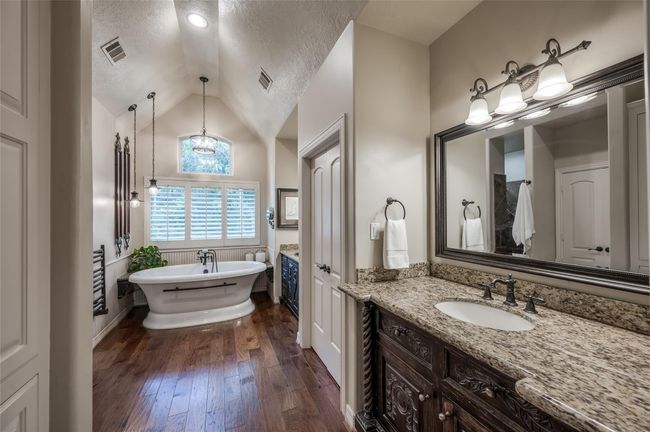 Experience luxury living with a stunning cathedral ceiling, expansive windows, and a spacious layout featuring dual custom vanities. Relax in the freestanding aerated soaker tub, enhanced by extensive lighting. | Image 15