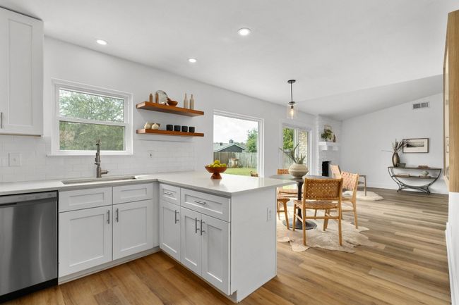 Kitchen with dishwasher, light wood finished floors, decorative backsplash, a peninsula, and light countertops | Image 7
