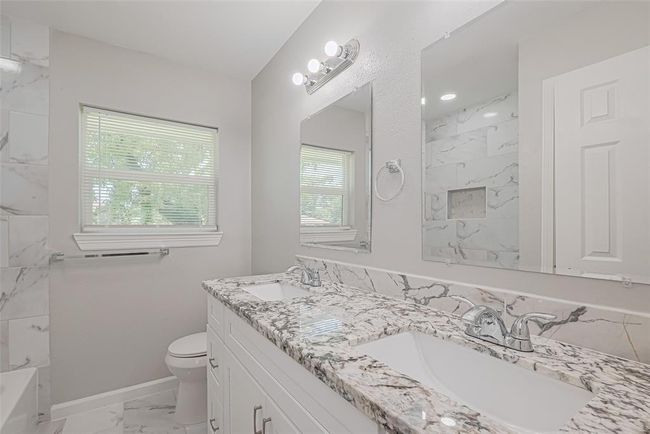This bathroom also features a dual-sink vanity, twin mirrors, under-cabinet storage, and a window for light and ventilation. | Image 25