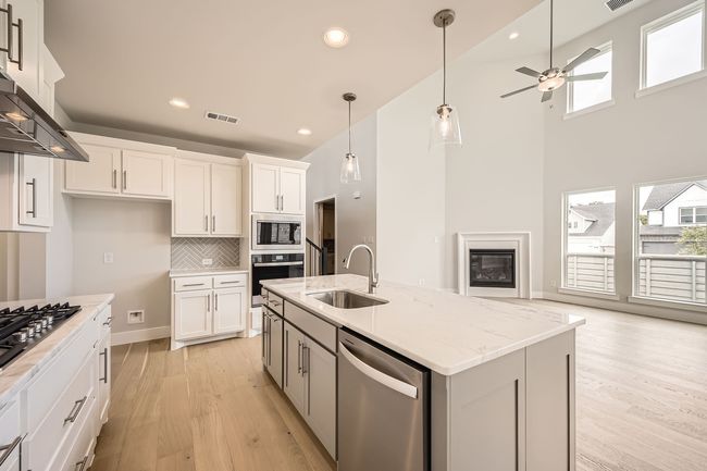 Kitchen featuring stainless steel appliances, light wood-style flooring, ceiling fan, wall chimney exhaust hood, and white cabinets | Image 13