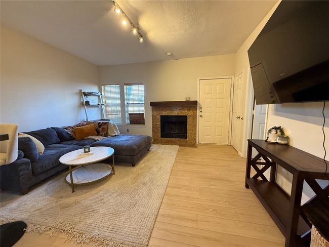 Living room with light wood-type flooring, a fireplace, track lighting, and a textured ceiling | Image 21