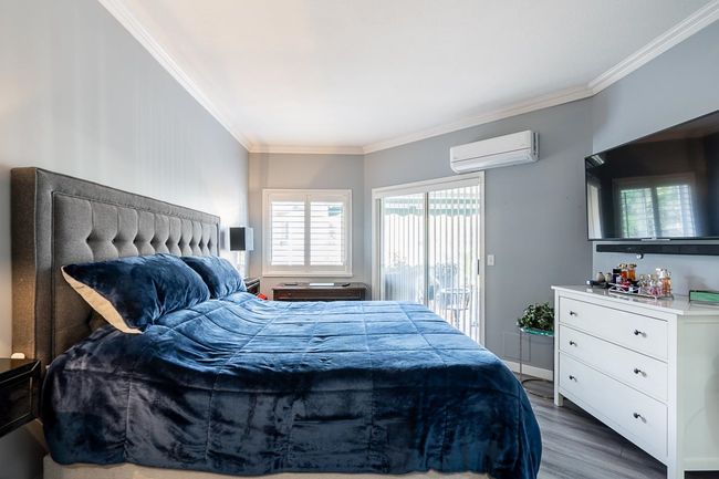 Bedroom featuring a wall unit AC, crown molding, wood finished floors, and access to exterior | Image 15