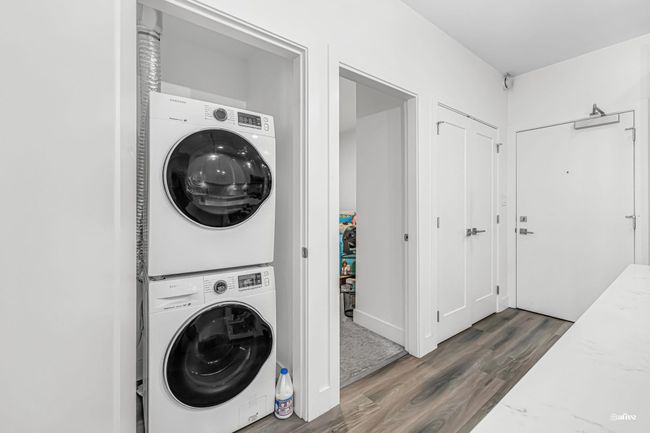 Laundry area with estacked washer and dryer and wood finished floors | Image 11