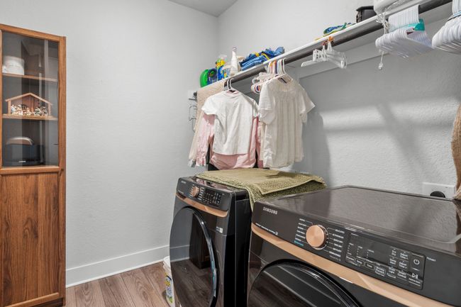 Washroom featuring wood finished floors, a textured wall, and washing machine and dryer | Image 28