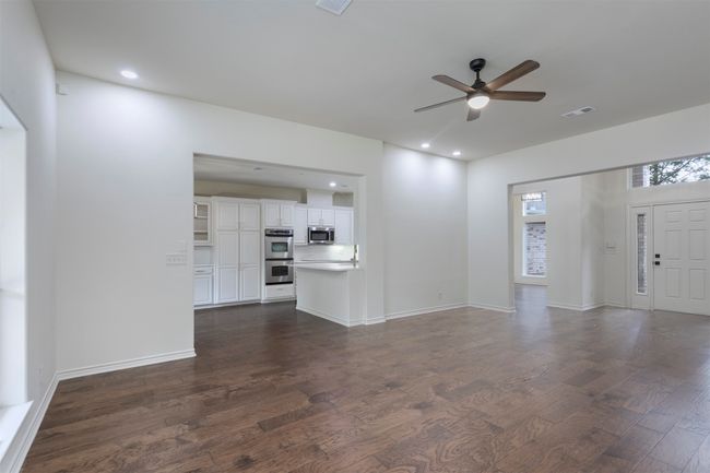 Unfurnished living room with a ceiling fan, dark wood finished floors, recessed lighting, and baseboards | Image 10