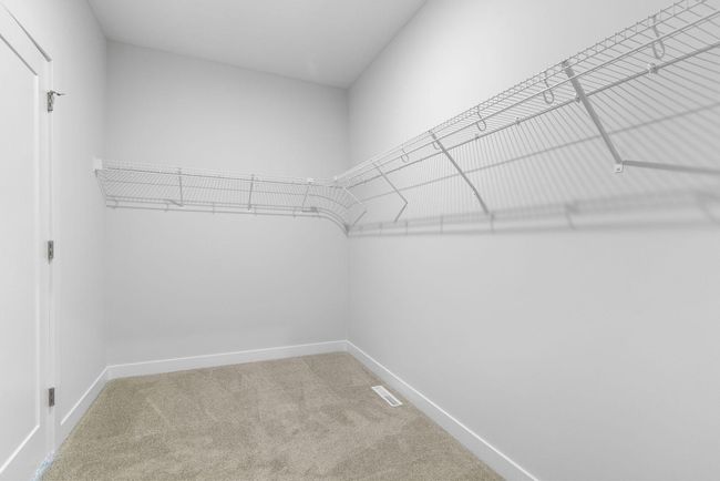 This expansive walk-in closet offers an abundance of space for all your wardrobe needs, with plenty of hanging room, and a well-organized layout conveniently connected to both the primary suite and the laundry. | Image 26