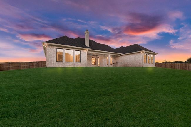 Back of property at dusk featuring brick siding, a chimney, and a fenced backyard | Image 5