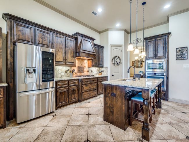 Kitchen featuring stainless steel appliances, a sink, tasteful backsplash, custom exhaust hood, and light stone counters | Image 10