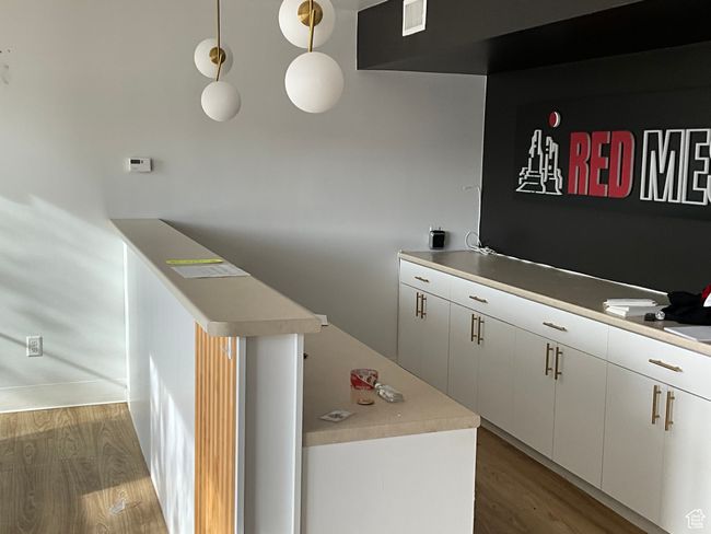 Kitchen featuring white cabinets, visible vents, light countertops, and wood finished floors | Image 12
